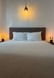 een slaapkamer met een bed met witte kussens en 2 verlichting bij Romeu in Quarteira
