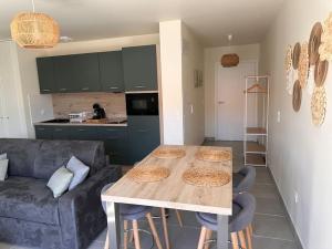 a kitchen and living room with a table and a couch at La Cabane Nature 400m de la plage in Mimizan