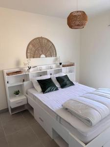 a bedroom with a large white bed with green pillows at La Cabane Nature 400m de la plage in Mimizan