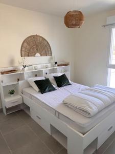 a white bed with two pillows on it in a room at La Cabane Nature 400m de la plage in Mimizan