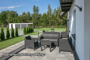 a patio with a table and chairs and a lawn at Apartamenty Zielona Lipka in Pisz