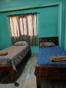 two beds in a room with blue walls at susurros del viento in Tilcara