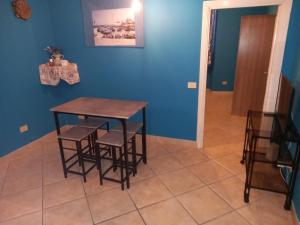 een tafel en stoelen in een kamer met een blauwe muur bij Appartamento nel cuore del centro storico in Valmontone