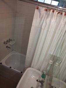 y baño con bañera y cortina de ducha. en Departamento calle 2 en La Plata