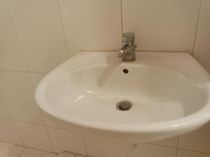 un lavabo blanco en un baño de azulejos blancos en Jordanian house, en Madaba