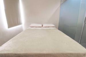 a bed in a white room with two pillows on it at Rumah Kayu Manis Bintaro in Jakarta