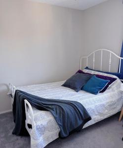 1 dormitorio con cama blanca y almohadas azules en Calgary Gorgeous Single House close LRT&UC&Free Parking en Calgary