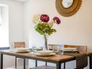 a dining room table with a vase of flowers on it at Bells Cottage - Explore Cornwall by rail in St Austell