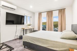 a bedroom with a large bed and a flat screen tv at Modern 3-Bed Apartment in Papaya Resort in Grote Berg