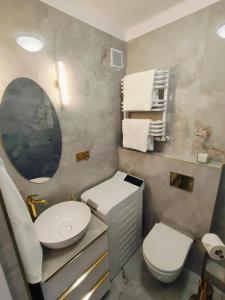W łazience znajduje się umywalka, toaleta i lustro. w obiekcie Apartament Inka w mieście Goleniów