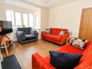 ein Wohnzimmer mit 2 Stühlen und einem roten Sofa in der Unterkunft The Chocolate Box in Weymouth