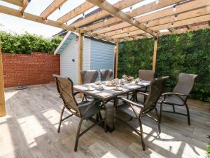 eine Terrasse mit einem Tisch und Stühlen unter einer Pergola in der Unterkunft The Chocolate Box in Weymouth