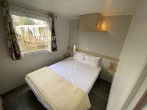 a small bedroom with a bed and a window at La cabane du lac in Aureilhan