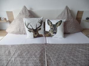 two stuffed deer heads on the pillows on a bed at Am Waldrand in Bayerisch Eisenstein