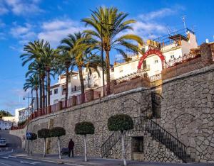 a building with palm trees behind a stone wall at La Viajera in Algarrobo