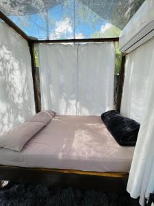 małe łóżko w namiocie z oknem w obiekcie Cabañas La Wereke w mieście Santiago