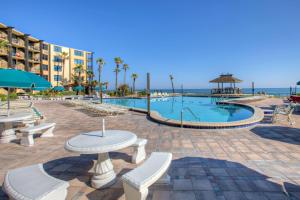 - une piscine avec une table et des chaises et l'océan dans l'établissement Beach Condo Unit #435, à Daytona Beach Shores