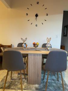 a dining room table with chairs and a clock on the wall at My Sweet Home in Tríkala