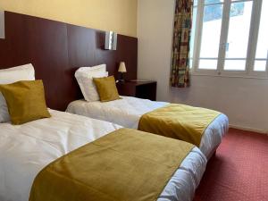 um quarto de hotel com duas camas e uma janela em HOTEL DE LISIEUX em Lourdes
