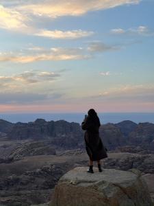 瓦迪穆薩的住宿－Petra Desert Dream Hotel，站在岩石上,拍着沙漠照片的女人