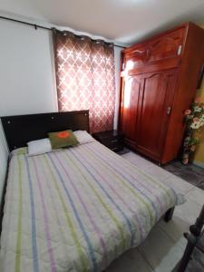 a bedroom with a large bed and a wooden cabinet at Habitacion privada en casa familiar con bano compartido in Armenia