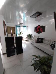 a white living room with a white couch and a room at Habitacion privada en casa familiar con bano compartido in Armenia