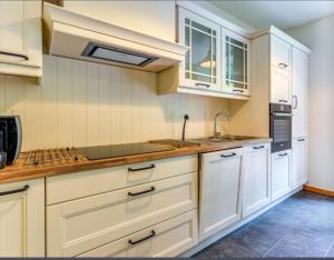 a kitchen with white cabinets and a sink at 6 bedrooms mansion with sauna enclosed garden and wifi at Aywaille in Aywaille