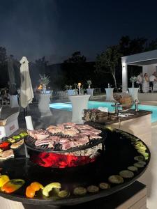 ein Buffet mit Speisen auf einem Tisch neben einem Pool in der Unterkunft Luxury Villa Mojito in Široki Brijeg