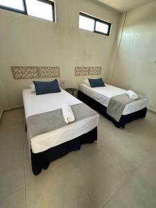 two beds in a room with two windows at Hotel Casa Prisca in Coyuca