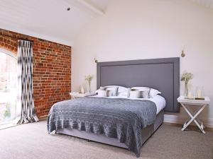 a bedroom with a large bed and a brick wall at The Piggery in Ledbury