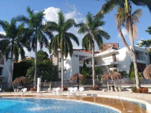 uma piscina com cadeiras e guarda-sóis em frente a um edifício em Apartasol Santa Fe de Antioquia em Santa Fe de Antioquia