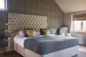 um quarto com uma cama grande e uma grande cabeceira. em The Stables em Ledbury