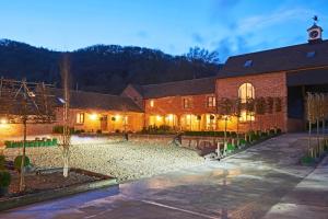 um grande edifício de tijolos com um pátio à noite em The Stables em Ledbury