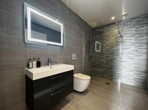 een badkamer met een wastafel, een toilet en een spiegel bij Laurel Cottage in Sandown