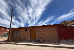 a brick building with a wooden door and a cloudy sky at Casa Once in San Pedro de Atacama