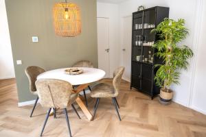 a dining room with a white table and chairs at Kahakai Beach House - Unique Outdoor Kitchen - next to local lake and 15 min. the from beach in Noordwijkerhout