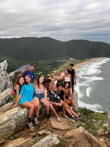 um grupo de pessoas sentadas numa rocha perto do oceano em Nômades Beach Hostel em Florianópolis