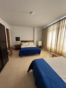 a bedroom with two beds and a large window at Hotel Armenia Centro in Armenia
