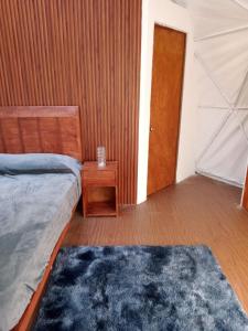 a bedroom with a bed and a table and a door at Glamping Don Delfis in Valle de Bravo