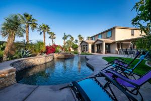 a house with a swimming pool and two lawn chairs at Coachella Play - 6BR Multi-Gen Fun Zone and Retreat with free heated pool in Indio