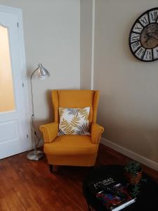 a orange chair with a pillow in a room with a clock at Zona centro con plaza de garaje VUT3983AS in Gijón