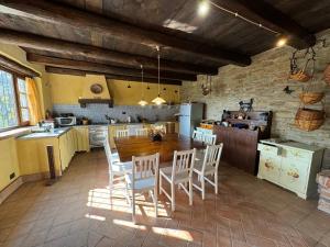 eine große Küche mit Holztisch und Stühlen in der Unterkunft Villa Natura Piemonte with pool in Castino
