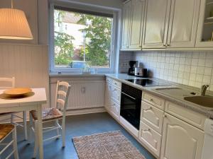 uma cozinha com armários brancos, uma mesa e uma janela em Haus-Jenina-Ferienwohnung em Cuxhaven