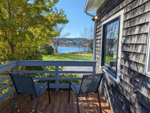 two chairs on a porch with a view of a lake at Beachy Watering Cove Cottage NEW in Prospect Harbor