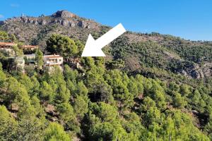 uma casa no topo de uma montanha com uma seta branca em casa en un parque natural em Las Villas
