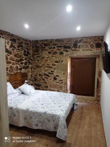 a bedroom with a bed and a stone wall at Casa Rueiro in A Pobra do Caramiñal