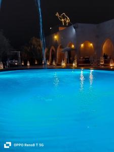 een groot blauw zwembad 's nachts bij Hotel Riad Ali in Merzouga