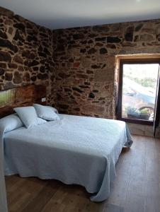 a bedroom with a bed with a stone wall at Casa Rueiro in A Pobra do Caramiñal