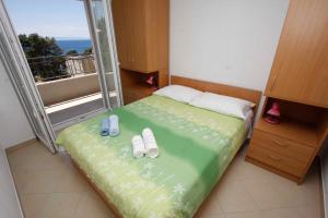 - une chambre avec un lit avec des tongs et un balcon dans l'établissement Apartmani NEVA, à Makarska
