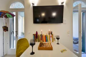 a table with books and candles and a tv on a wall at Τhe Hidden Garden in Corfu Town